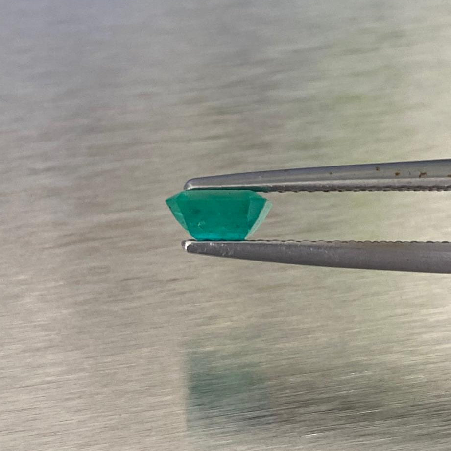 0.51 ct natural Muzo Colombian emerald held in tweezers, side profile view