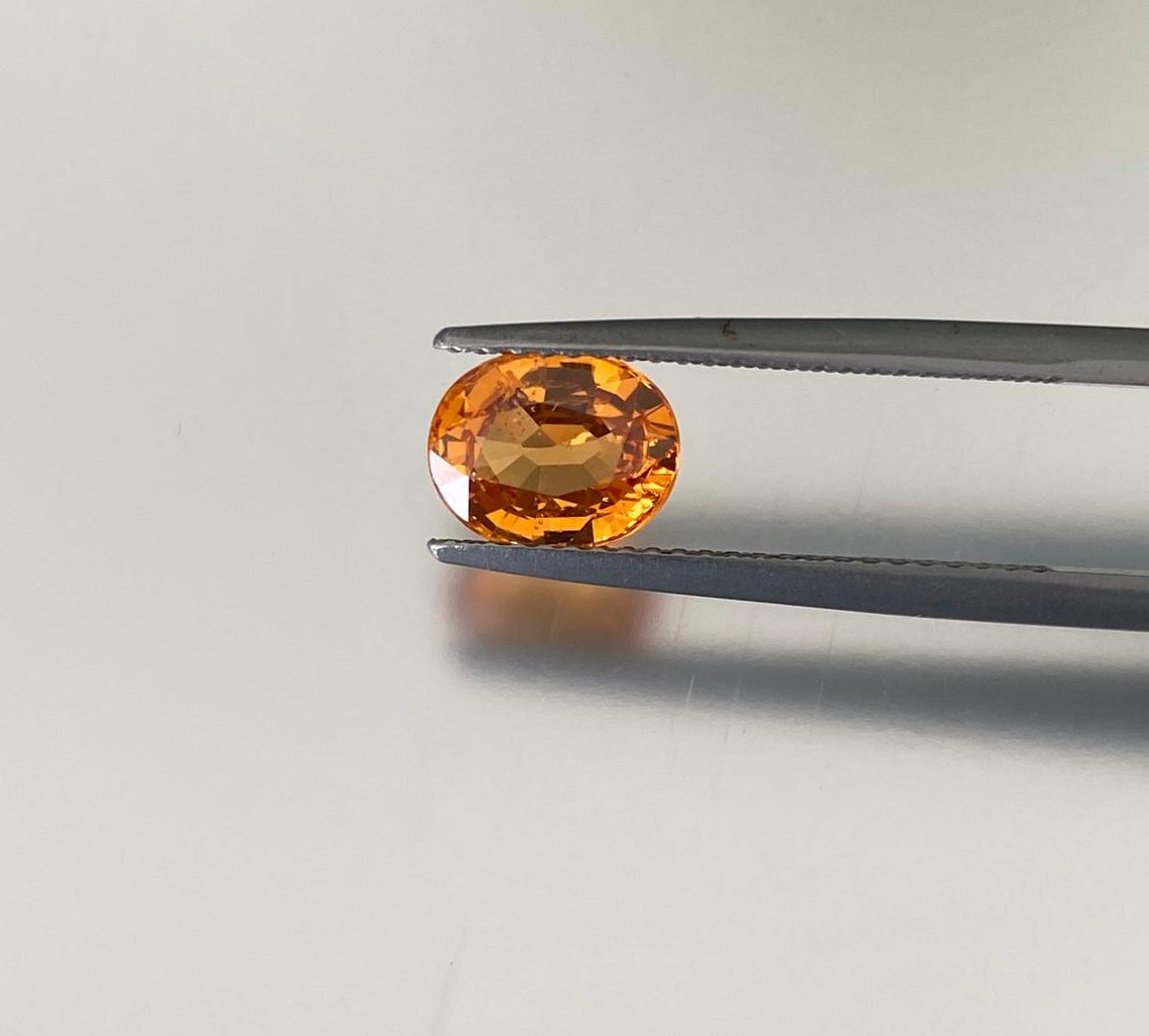 2.14 ct orange spessartite garnet, face-up view held in gemological tweezers