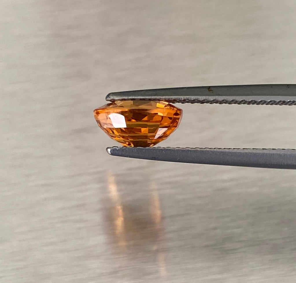 2.14 ct orange spessartite garnet, profile view held in gemological tweezers