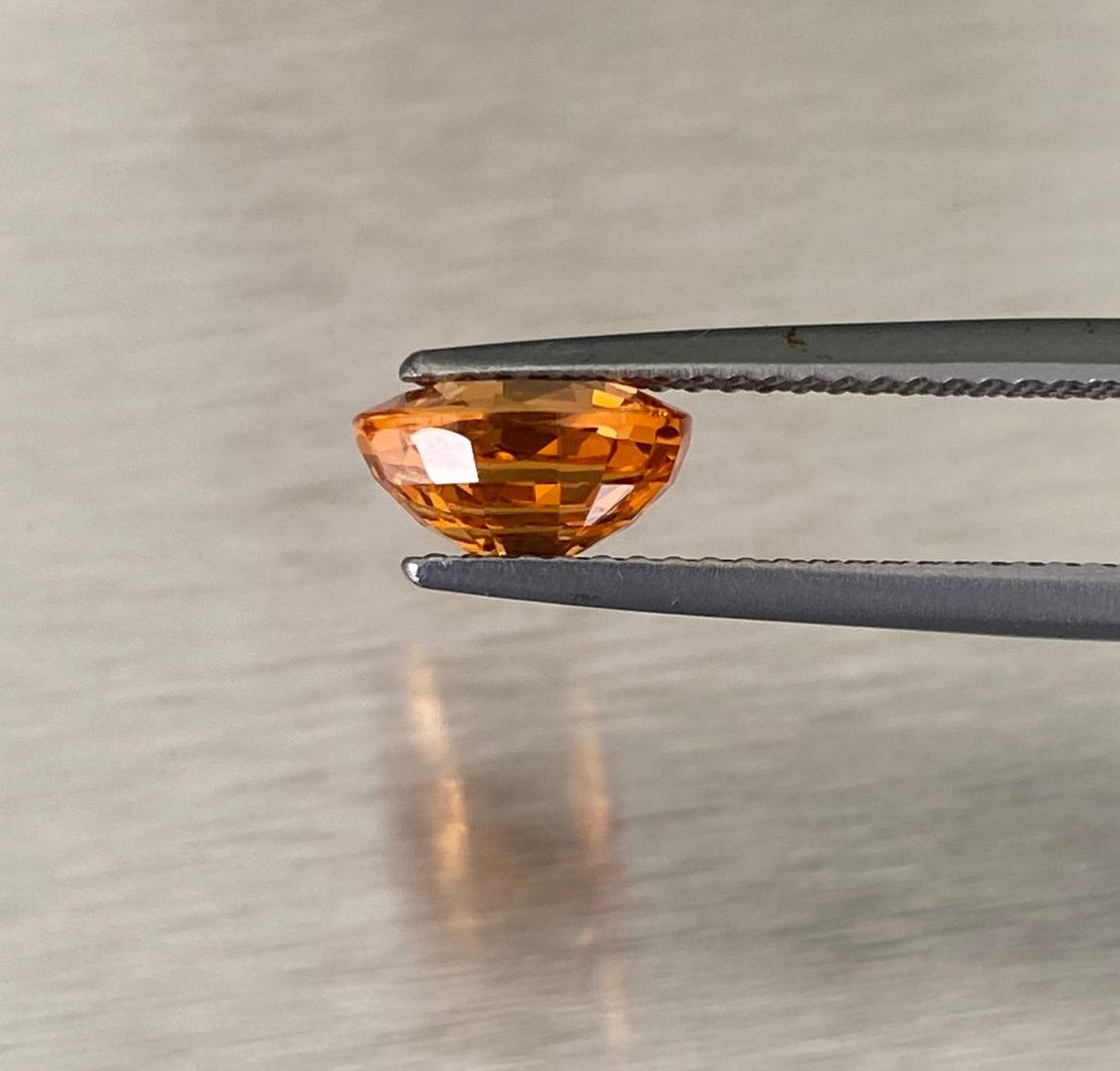 2.14 ct orange spessartite garnet, profile view held in gemological tweezers
