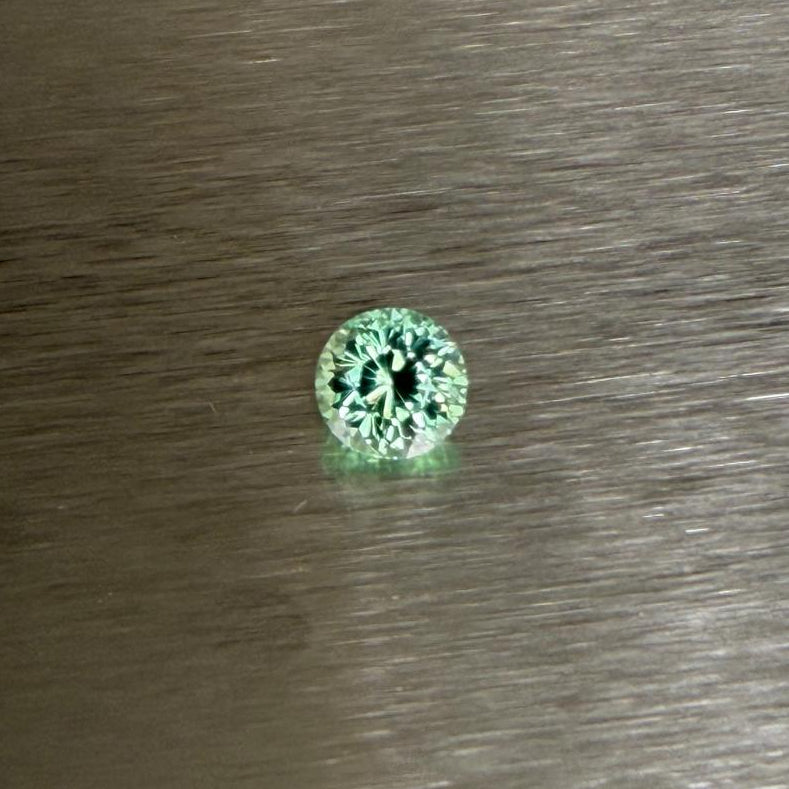 1.70 ct Merelani mint grossular garnet held face-up in tweezers, round modified brilliant cut, Otzera OTZ-2026-01636