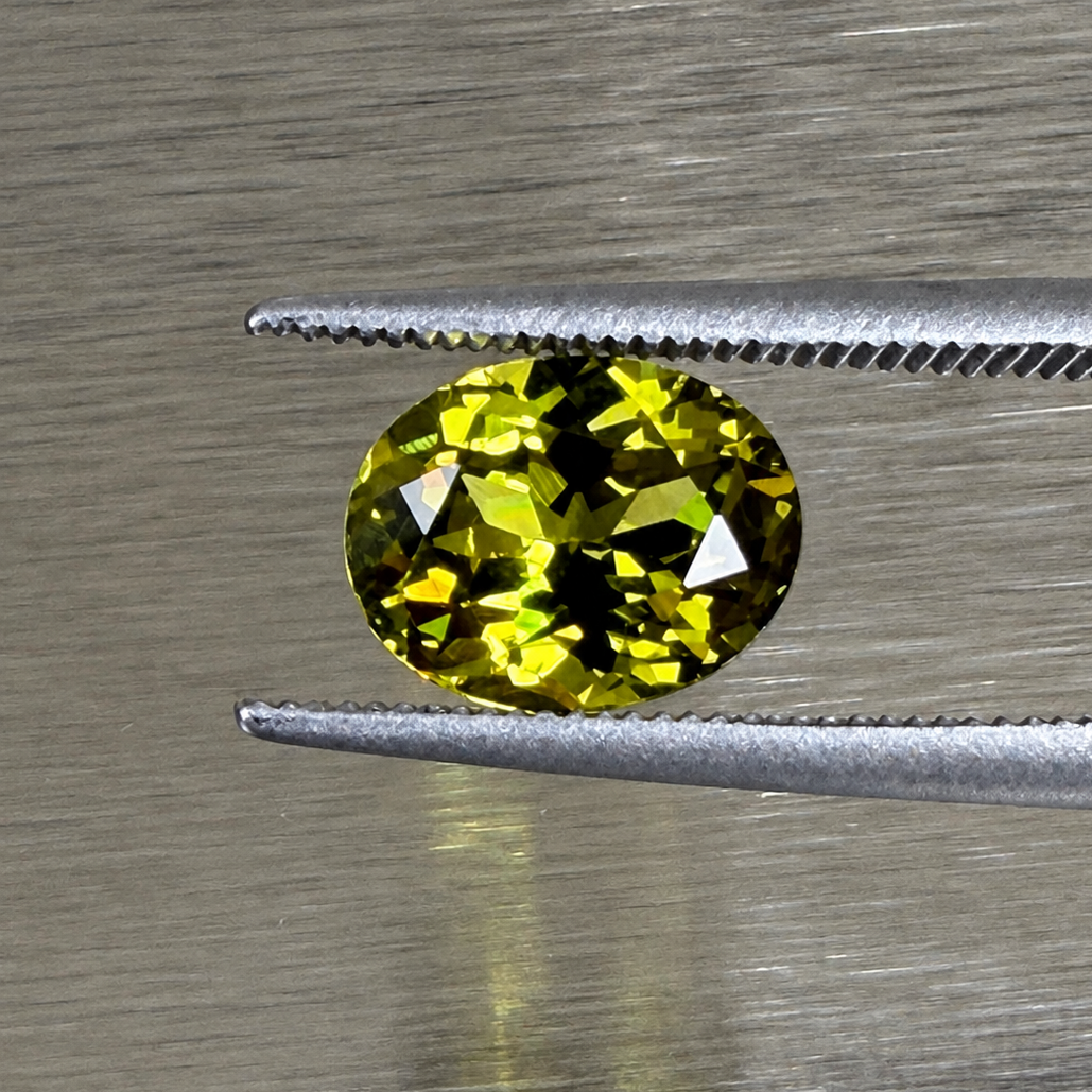 2.22 ct natural Andradite garnet oval modified brilliant held in tweezers