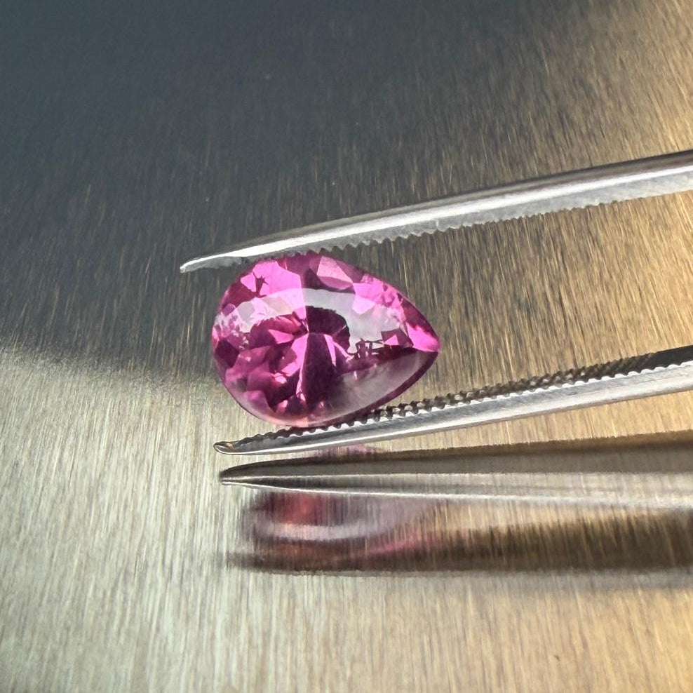 3.19 ct raspberry rhodolite garnet in a pear-shaped buff-top mixed cut, tweezer face-up view, Otzera OTZ-2026-01649