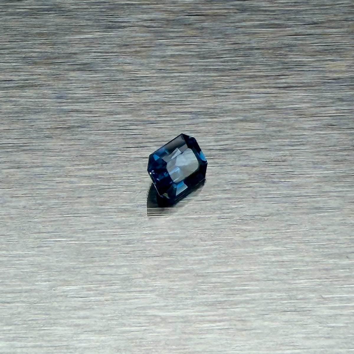 1.00 ct blue sapphire, emerald cut, angled view showing blue flashes, Otzera OTZ-2026-01660
