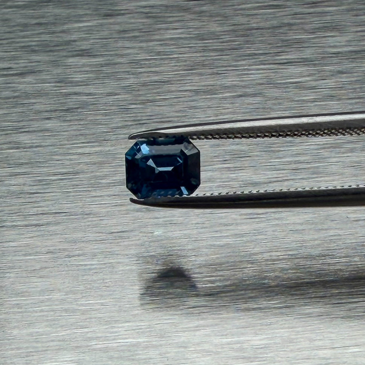 1.00 ct heated blue sapphire held in tweezers, face-up emerald-cut view, Otzera OTZ-2026-01660