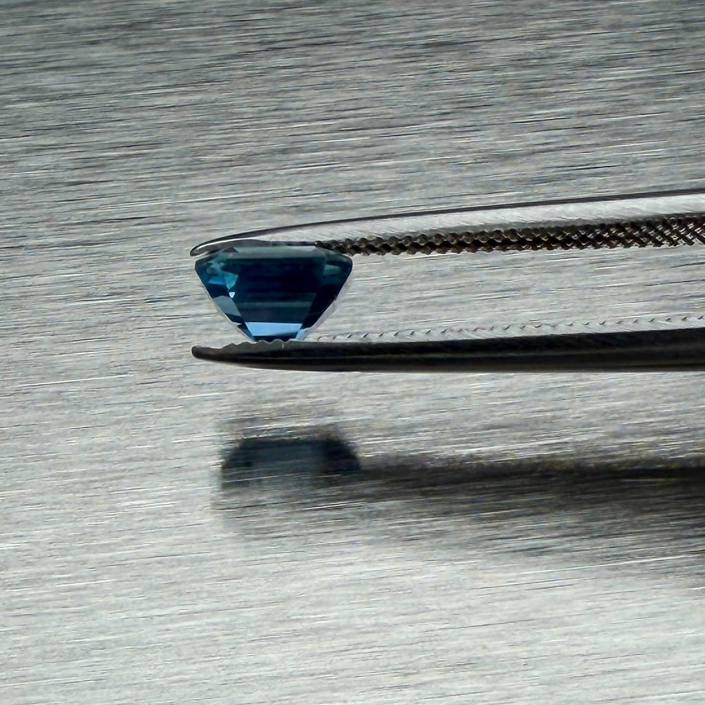1.00 ct blue sapphire held in tweezers, side profile showing cut depth, Otzera OTZ-2026-01660