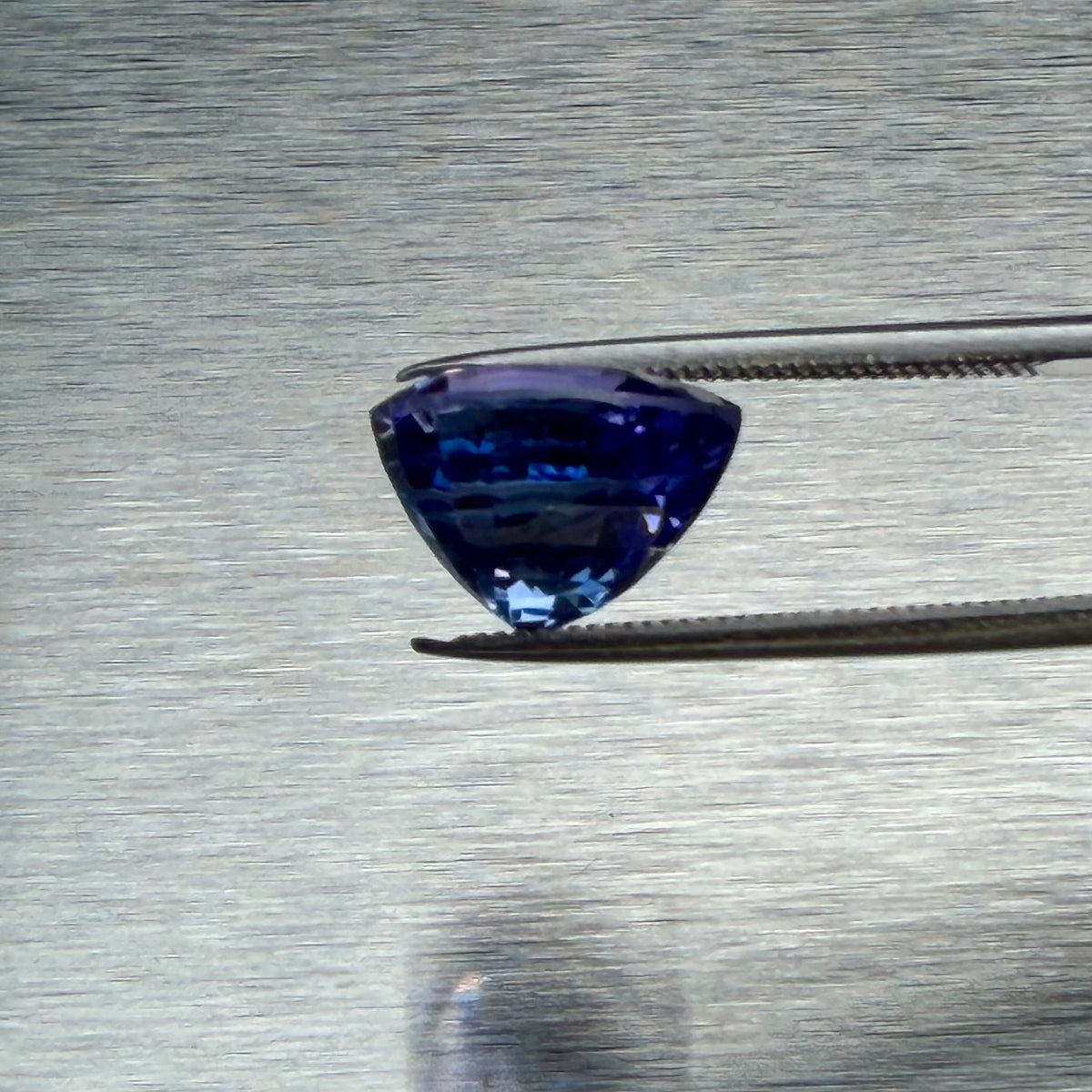 6.75 ct tanzanite held in tweezers, side profile showing cut depth, Otzera OTZ-2026-01661