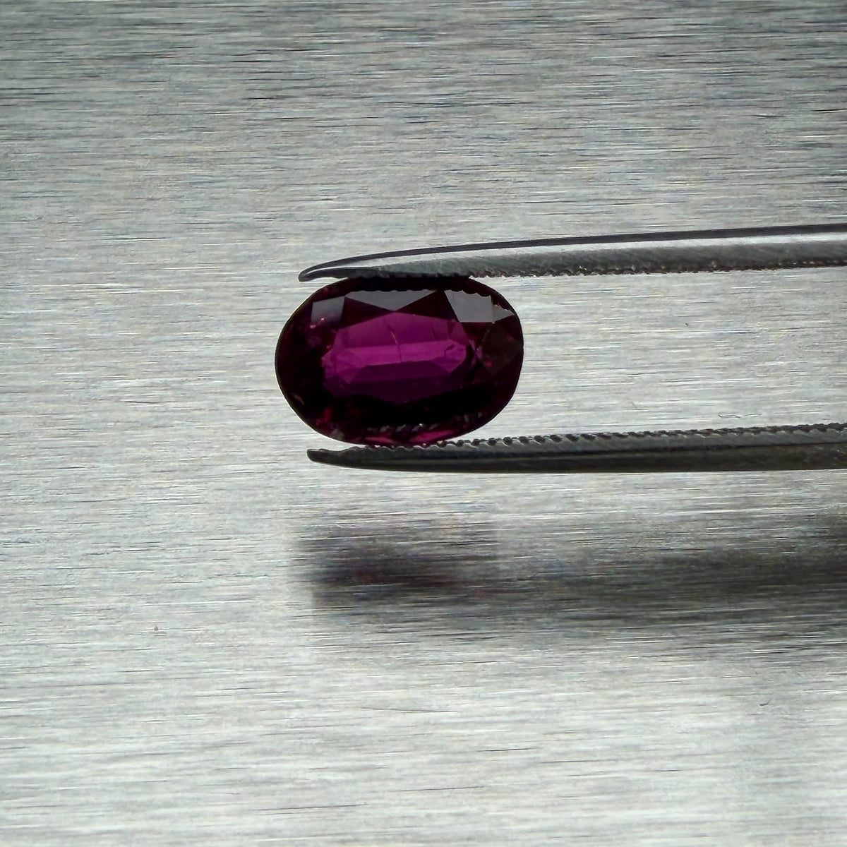 1.82 ct heated natural ruby held in tweezers, face-up oval view, Otzera OTZ-2026-01662