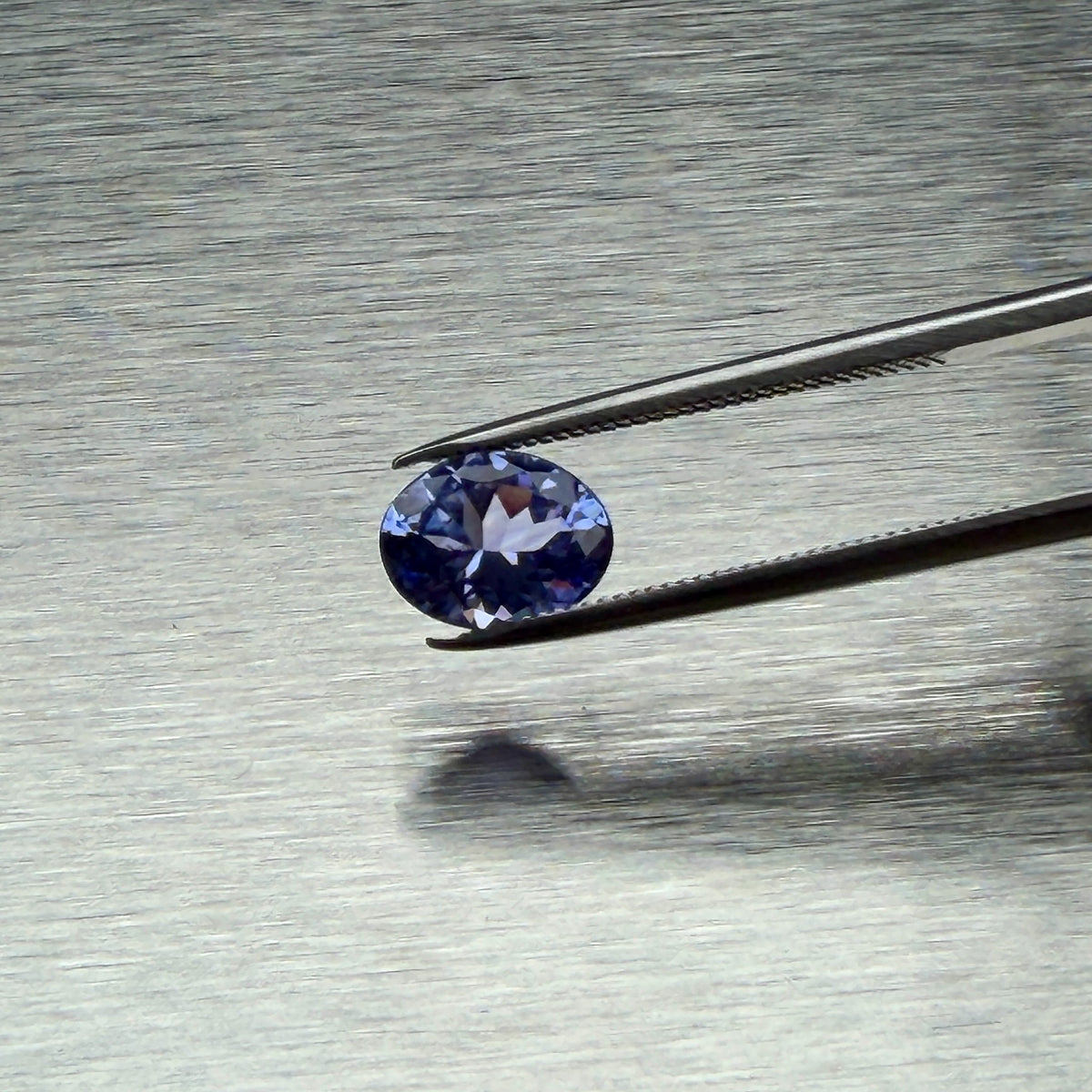 1.44 ct natural tanzanite held in tweezers, face-up oval view, Otzera OTZ-2026-01664