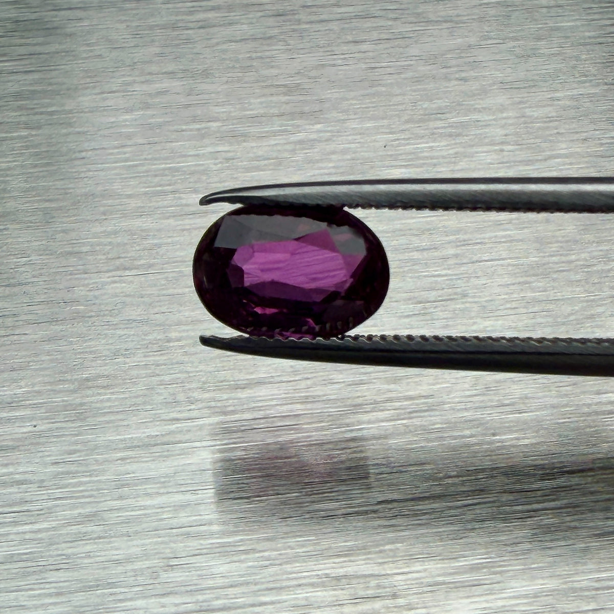 1.66 ct natural unheated ruby held in tweezers, face-up oval view, Otzera OTZ-2026-01665