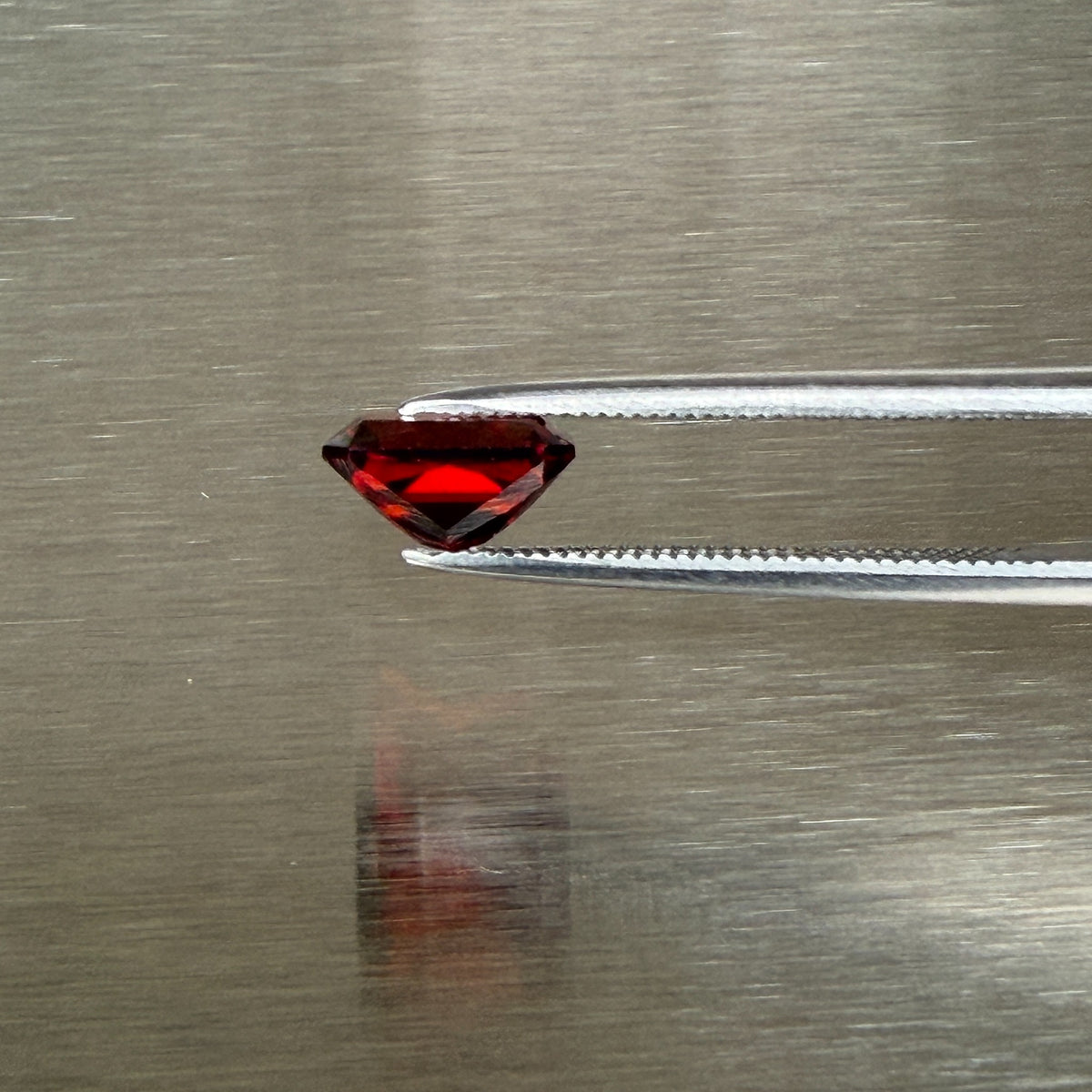 2.18 ct Nigerian spessartite garnet held in tweezers, side profile showing precision cut, Otzera OTZ-2026-01668