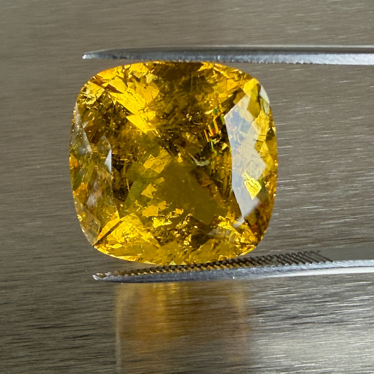 23.93 ct golden beryl heliodor held in tweezers, face-up cushion view, Otzera OTZ-2026-01670