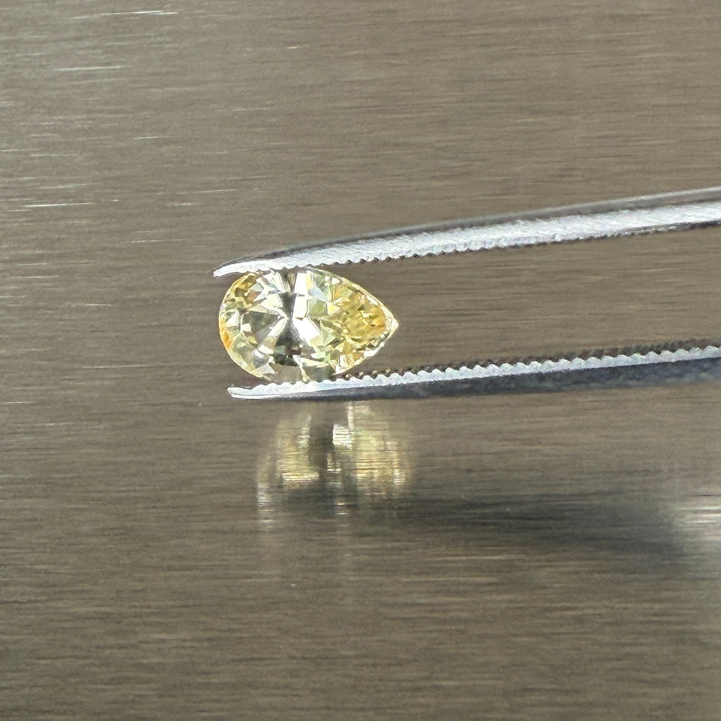 1.24 ct unheated yellow sapphire held in tweezers, face-up pear view, Otzera OTZ-2026-01671