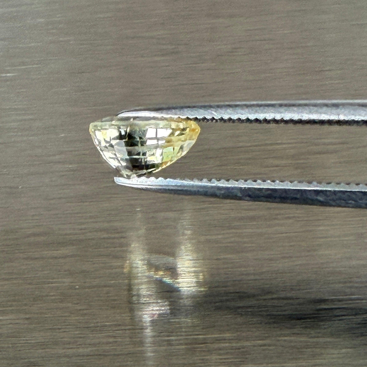1.24 ct unheated yellow sapphire held in tweezers, side profile showing cut depth, Otzera OTZ-2026-01671