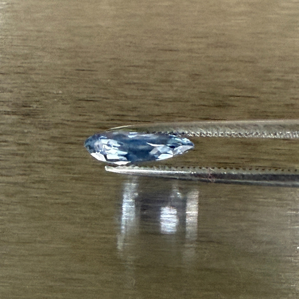 2.44 ct unheated blue sapphire held in tweezers, side profile showing shallow cut, Otzera OTZ-2026-01672