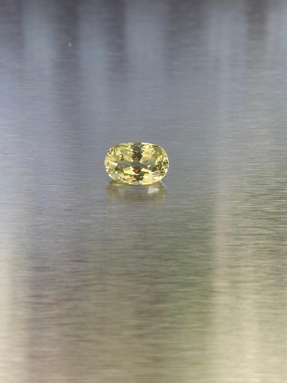 3.83 ct natural yellow chrysoberyl, face-up oval view on a brushed silver background.