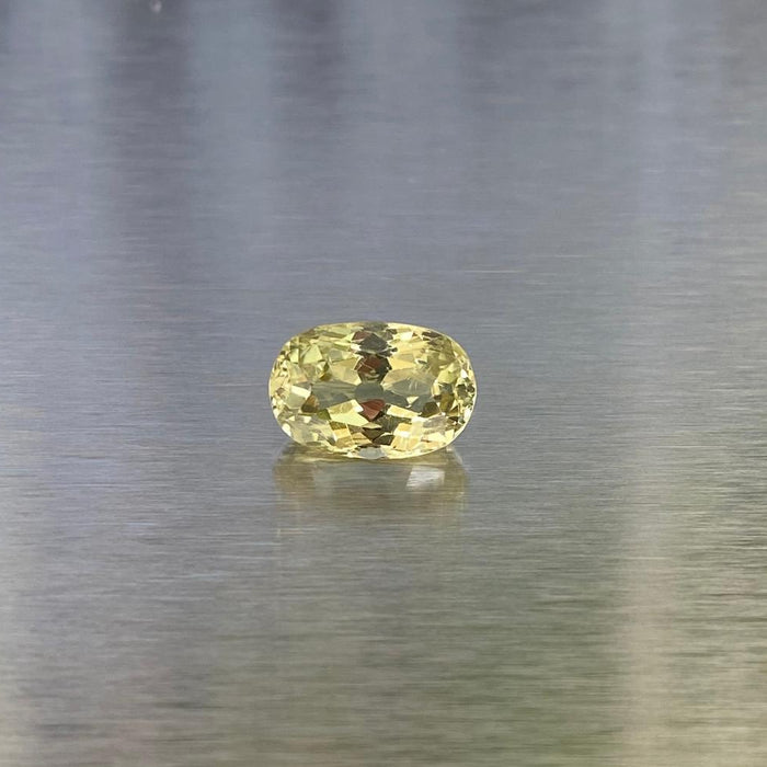 3.83 ct natural yellow chrysoberyl, face-up oval view on a brushed silver background.