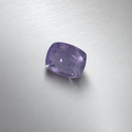 A cushion-cut purple sapphire, displayed on a brushed silver metal surface.